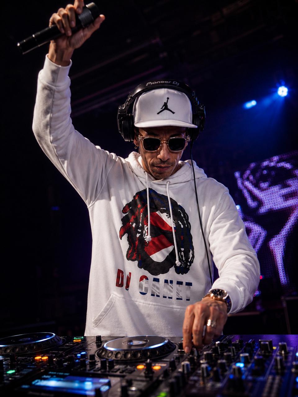 DJ Canet en directo con el micrófono en alto y la otra mano en el controlador