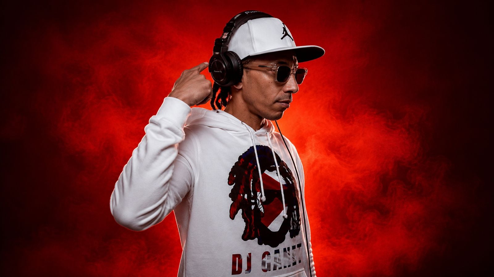 DJ Canet de perfil con la mano en los auriculares, sobre humo rojo